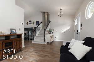 Entrance foyer featuring lofted ceiling, a notable chandelier, and hardwood / wood-style floors