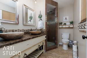 Bathroom with a shower with door, vanity, and toilet