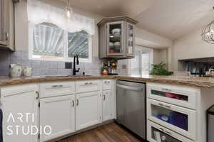 Kitchen with sink, dishwasher, hanging light fixtures, backsplash, and dark hardwood / wood-style flooring