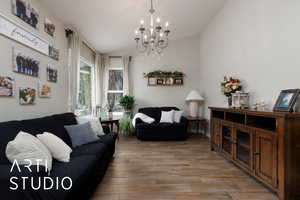 Living room with lofted ceiling, a notable chandelier, and light wood-type flooring