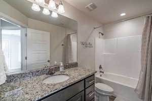 Full bathroom featuring toilet, vanity, and shower / bathtub combination with curtain