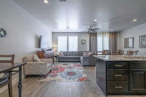 Living room with sink, a textured ceiling, ceiling fan, and light hardwood / wood-style flooring