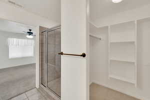 Bathroom featuring tile patterned flooring, a shower with door, and ceiling fan