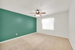 Carpeted empty room featuring a textured ceiling and ceiling fan