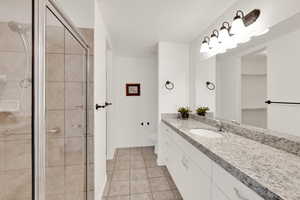 Bathroom featuring tile patterned flooring, vanity, a textured ceiling, toilet, and walk in shower