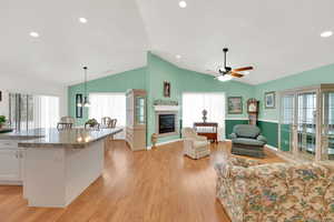 Interior space featuring vaulted ceiling, ceiling fan, a tiled fireplace, and light hardwood / wood-style floors