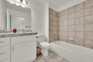 Full bathroom with tiled shower / bath, vanity, toilet, and tile patterned flooring