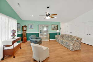 Living room with ceiling fan, lofted ceiling, and light hardwood / wood-style flooring