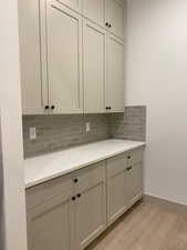 Interior space with gray cabinets, backsplash, and light wood-type flooring