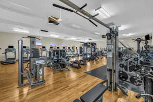 Exercise room with hardwood / wood-style floors and ceiling fan