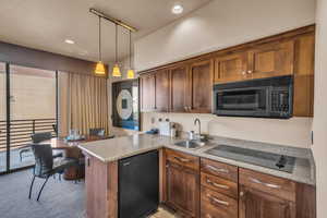 Kitchen featuring sink, decorative light fixtures, kitchen peninsula, light colored carpet, and black appliances