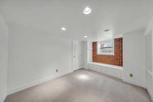 Spare room featuring brick wall and light carpet