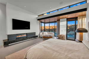 Bedroom with access to exterior, a premium fireplace, and a wall of windows
