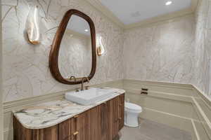 Bathroom with wallpapered walls, vanity, light tile patterned floors, recessed lighting, and ornamental molding