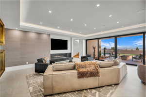 Living area featuring a raised ceiling, recessed lighting, a high end fireplace, and stairs