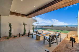 View of patio / terrace featuring a fire pit, a mountain view, and a tennis court