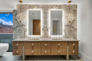 Full bath with double vanity, tile walls, light tile patterned floors, and stone wall