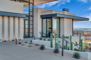 Property entrance with stucco siding, a mountain view, and a chimney