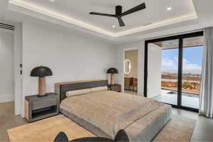 Bedroom featuring a raised ceiling, expansive windows, access to exterior, recessed lighting, and a ceiling fan