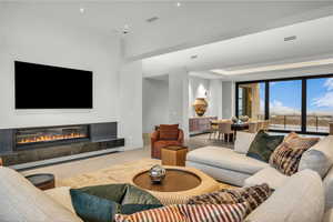 Tiled living room with a high end fireplace, recessed lighting, and a tray ceiling
