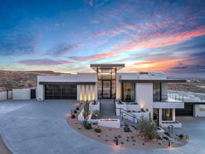 Modern home with stucco siding, concrete driveway, an outdoor fire pit, and an attached garage