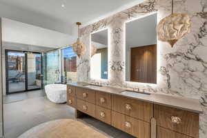 Bathroom with tile walls, double vanity, stone wall, a freestanding tub, and a stall shower