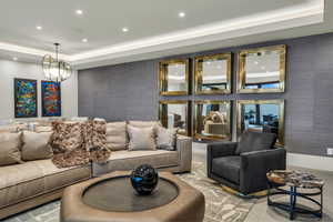 Living room featuring a tray ceiling, recessed lighting, and wallpapered walls