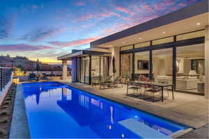 Pool at dusk with a patio, an outdoor hangout area, and exterior kitchen