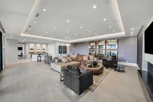 Living area with a raised ceiling, recessed lighting, a fireplace, and light tile patterned flooring