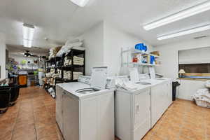 Community laundry room featuring ceiling fan, separate washer and dryer, a textured ceiling, and light tile patterned flooring