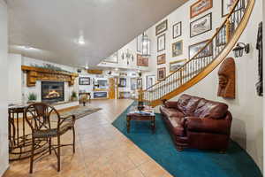 Living area featuring light tile patterned floors, stairway, a glass covered fireplace, and a textured ceiling