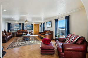 Living room featuring arched walkways, ornamental molding, light wood-style flooring, and a healthy amount of sunlight