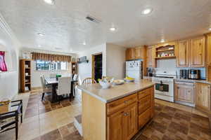 Kitchen featuring white appliances, visible vents, a kitchen island, light countertops, and open shelves