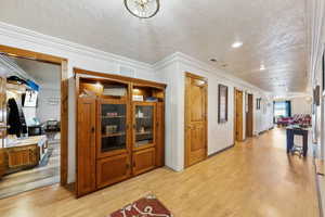 Corridor with light wood-style floors, visible vents, and a textured ceiling