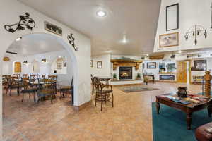 Tiled living room featuring arched walkways, visible vents, a glass covered fireplace, a textured ceiling, and baseboards