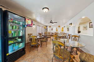 Dining area featuring light tile patterned floors, visible vents, arched walkways, ceiling fan, and a textured ceiling