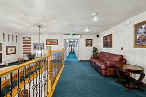 Living room with a textured ceiling, dark colored carpet, and baseboards