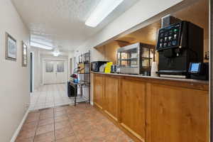 Kitchen with light tile patterned floors, french doors, a textured ceiling, and baseboards