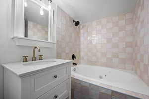 Bathroom featuring tiled shower / bath combo, vanity, and a textured ceiling