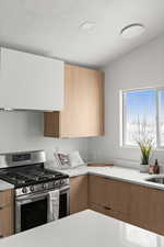 Kitchen with vaulted ceiling, sink, a textured ceiling, and stainless steel gas stove