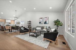 Living room with lofted ceiling, a healthy amount of sunlight, and light hardwood / wood-style flooring