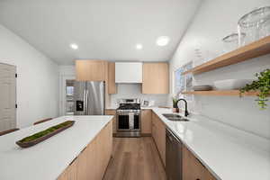 Kitchen featuring appliances with stainless steel finishes, sink, and light hardwood / wood-style flooring