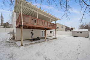 Snow covered rear of property featuring a shed and a deck