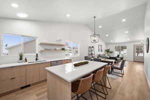 Kitchen with lofted ceiling, sink, a breakfast bar, a center island, and stainless steel dishwasher