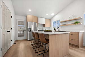 Kitchen featuring light wood-type flooring, stainless steel appliances, a center island, and a kitchen bar