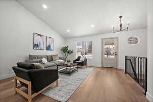 Living room with hardwood / wood-style flooring, high vaulted ceiling, and an inviting chandelier