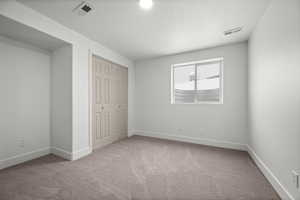 Unfurnished bedroom featuring light carpet, a textured ceiling, and a closet