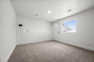 Carpeted empty room featuring a textured ceiling