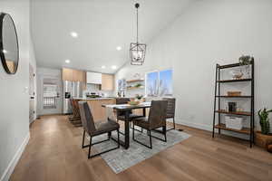 Dining room with an inviting chandelier, sink, high vaulted ceiling, and light wood-type flooring