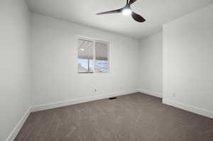 Empty room with dark carpet, a textured ceiling, and ceiling fan